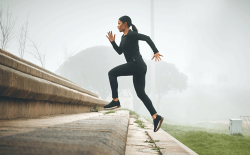 female active runner sprinting up stairs